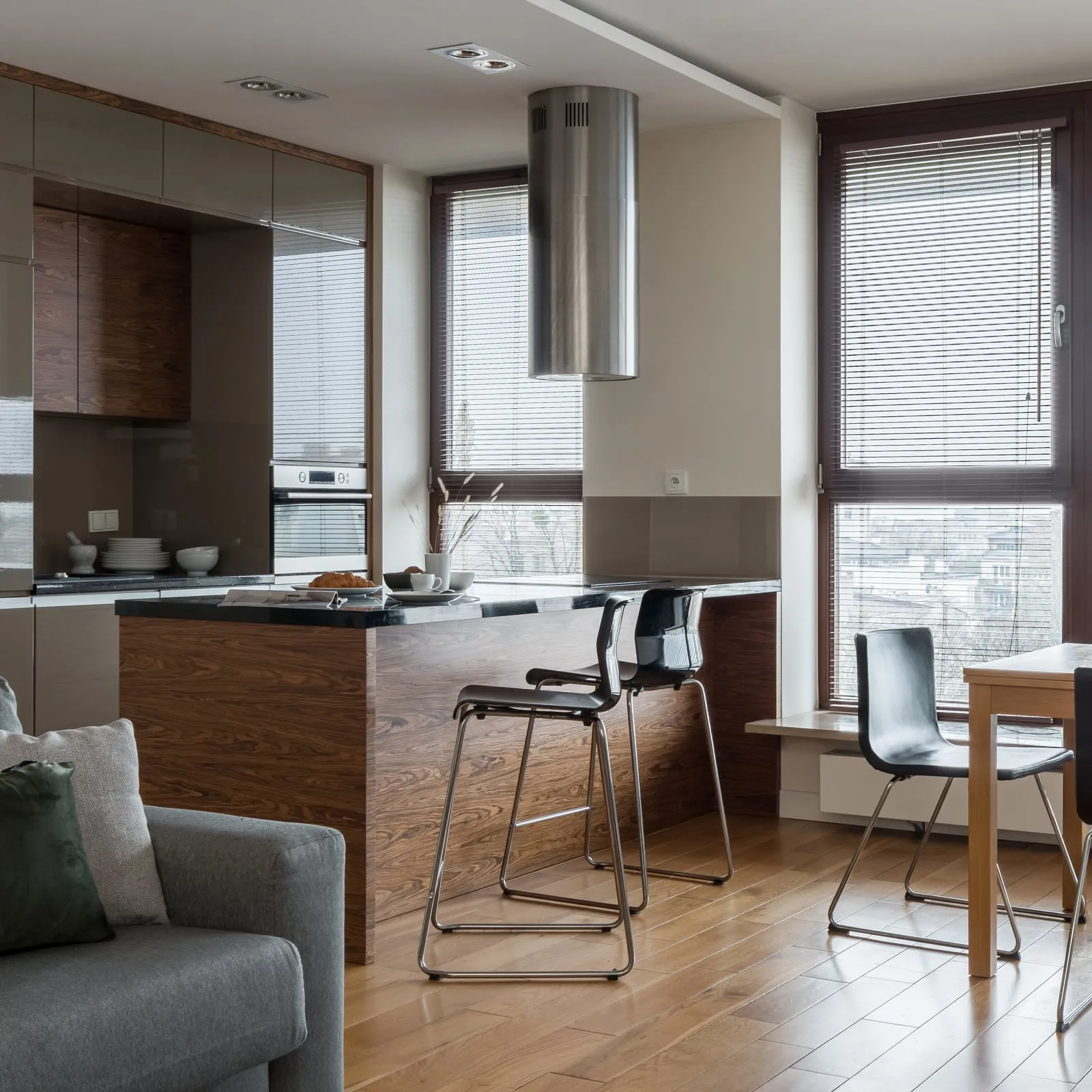 Moderne køkken med ø og barstole, der går over i en stue med sofa